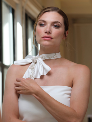 Model wearing floral and bead embellished bow with a strapless white dress