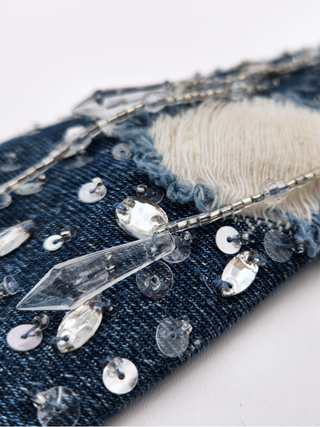 Close-up of denim frayed fabric, silver sequins and crystal tassels.