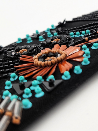 closeup of floral beadwork and embroidery detail featuring black, coral and turquoise beading