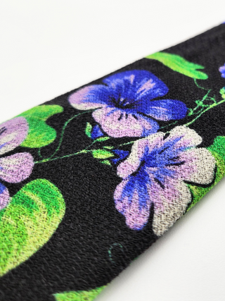 Close-up of floral print in purple and green on black background.
