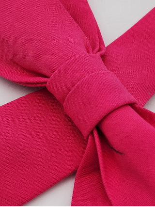 Close-up of a hot pink cotton fabric bow on a white background
