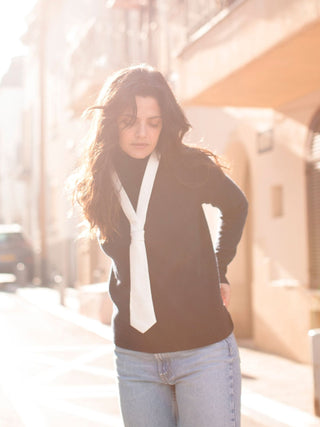 Model wearing a white and lurex plunge tie over a black turtleneck and jeans