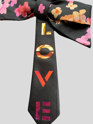 Closeup of hand painted word Love on black Bow tie with floral print