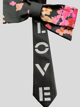 Closeup image of  silver hand painted word Love on black Bow tie with floral print