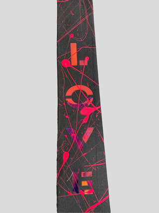 Closeup image of black classic necktie with the word Love painted in red with red splatter paint