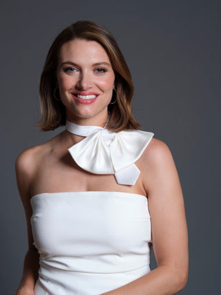 Female model wearing white silk charmeuse bow tie off center, with a white strapless dress