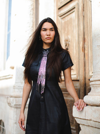Model wearing a black satin dress with a black embellished tie featuring rhinestones and beady fringe.