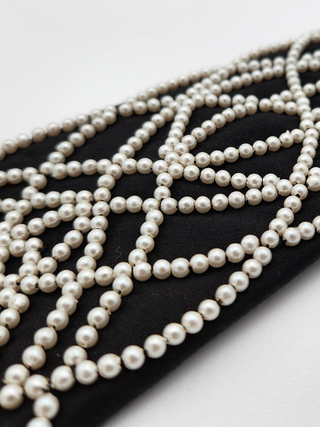 details of white pearl embroidery on black necktie