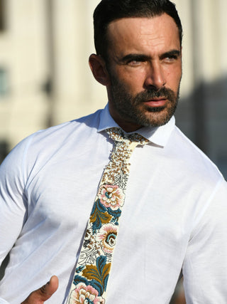 Male model wearing a spread collar white shirt with a floral and crystal embroidered necktie in pinks and blues