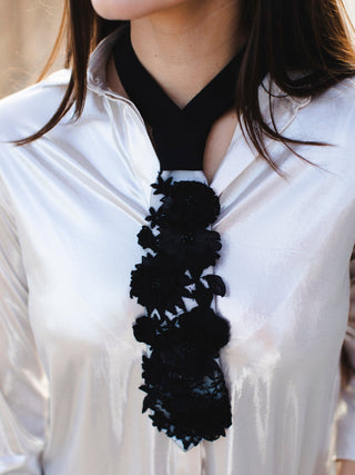 Model wearing a white petite tie with a black neckband and embroidered with silk flowers and glass beads.