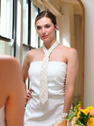Model wearing an ivory pearl embroidered tie styled with a white strapless dress